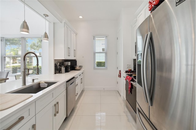 kitchen featuring backsplash, light tile patterned floors, white cabinets, stainless steel appliances, and a sink