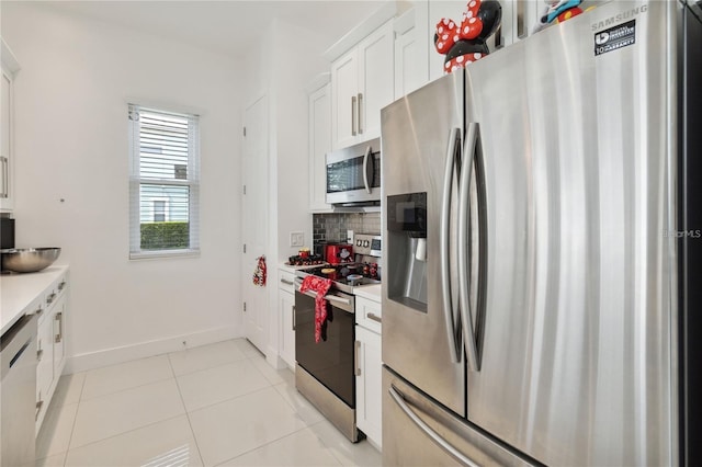 kitchen with tasteful backsplash, light countertops, light tile patterned floors, appliances with stainless steel finishes, and white cabinetry