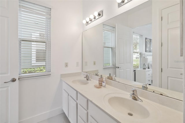 full bathroom featuring a sink, baseboards, and double vanity