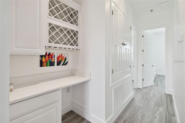 corridor featuring baseboards, visible vents, and light wood finished floors