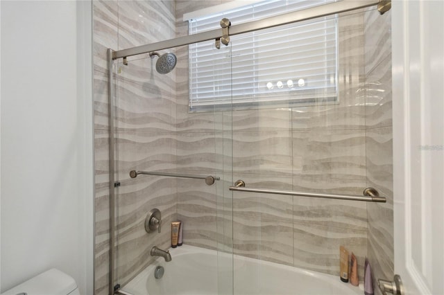 bathroom with toilet and shower / bath combination with glass door