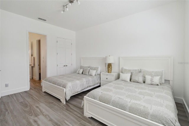 bedroom featuring visible vents, baseboards, a closet, and wood finished floors