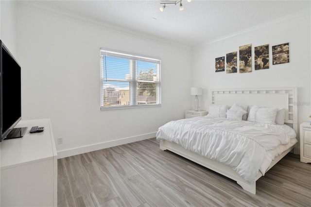 bedroom with wood finished floors, baseboards, and ornamental molding