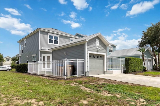 exterior space featuring fence, driveway, a garage, a lawn, and metal roof