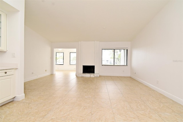 unfurnished living room with vaulted ceiling, baseboards, and a large fireplace