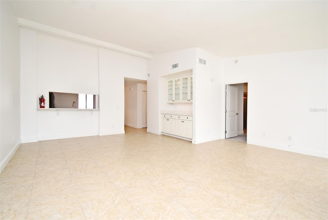 unfurnished living room featuring visible vents, baseboards, and lofted ceiling