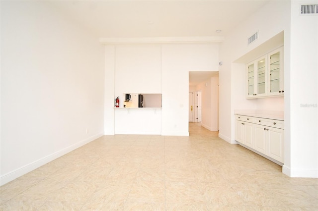 unfurnished living room featuring visible vents and baseboards