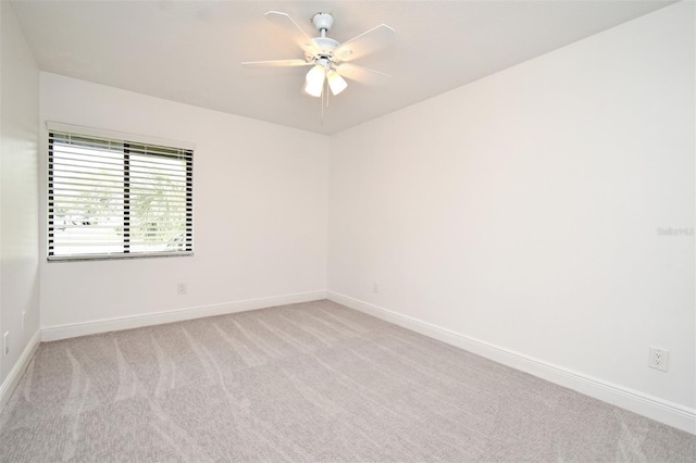 empty room featuring baseboards, light colored carpet, and a ceiling fan