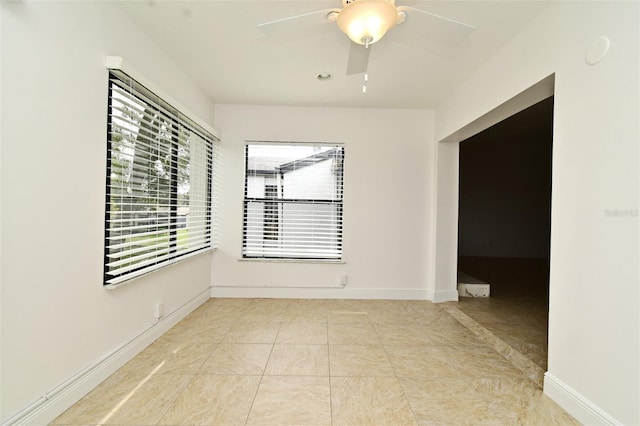 tiled spare room featuring ceiling fan and baseboards