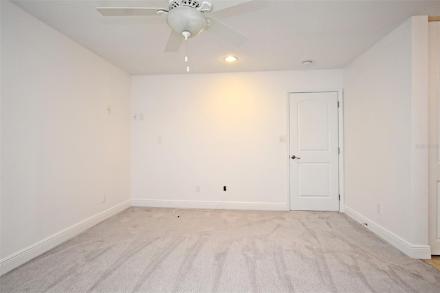 spare room featuring a ceiling fan, recessed lighting, light colored carpet, and baseboards