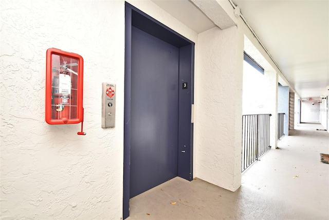 view of exterior entry featuring stucco siding and elevator