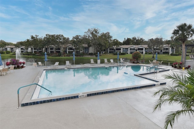 community pool with a patio area, fence, and a residential view