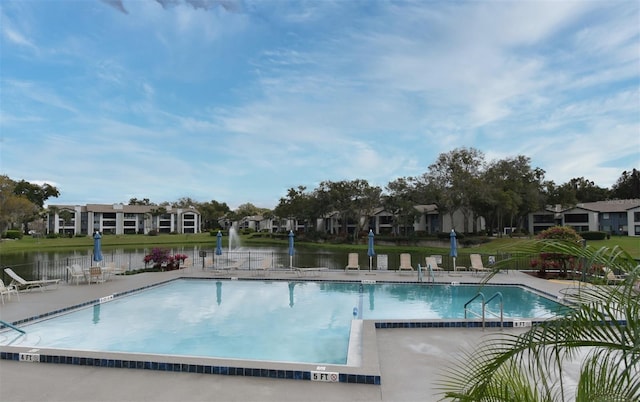 community pool featuring a patio area, fence, and a water view