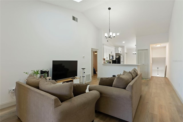 living room with light wood-type flooring, visible vents, baseboards, and a chandelier