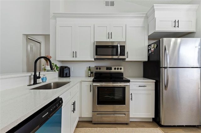 kitchen with light stone countertops, visible vents, a sink, stainless steel appliances, and white cabinets