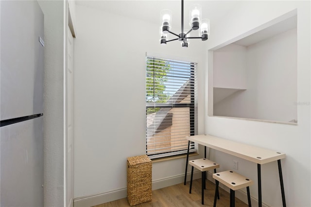 office featuring baseboards, an inviting chandelier, and light wood-style flooring