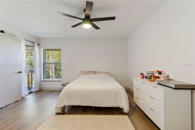 bedroom with baseboards, wood finished floors, a ceiling fan, and access to exterior