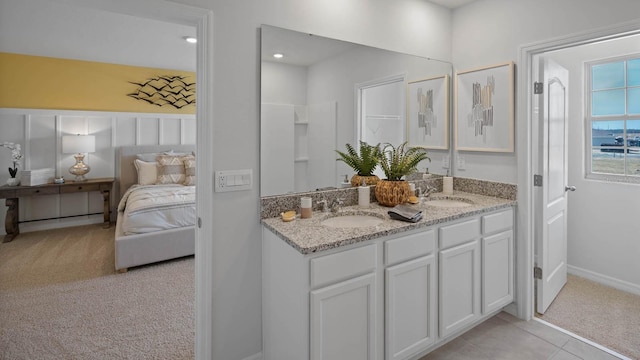 ensuite bathroom with a sink, baseboards, ensuite bathroom, and double vanity