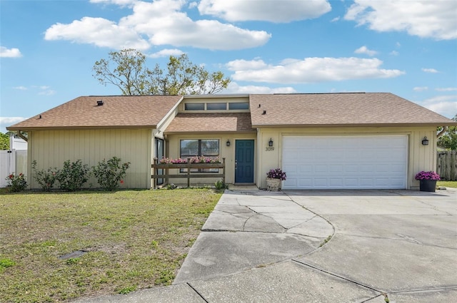 view of front of house with fence, concrete driveway, an attached garage, a shingled roof, and a front yard