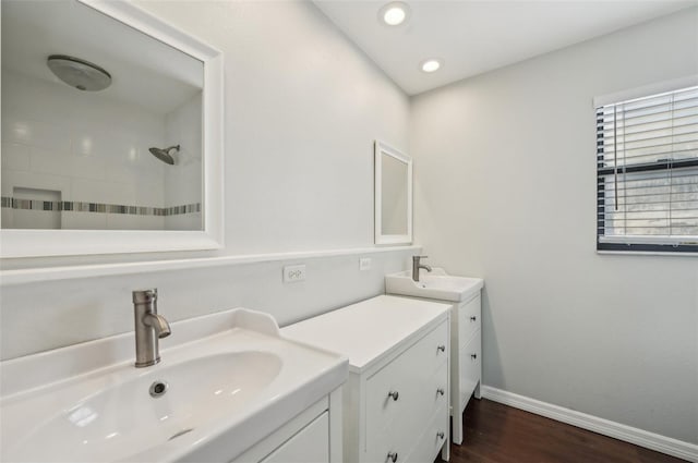 bathroom with a sink, baseboards, wood finished floors, and a tile shower