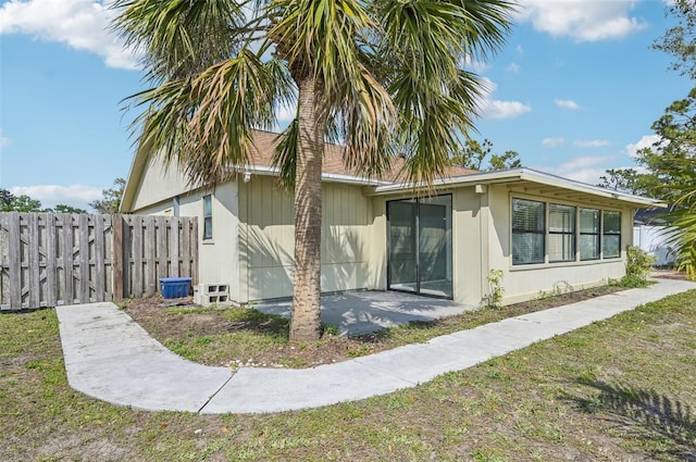 rear view of property featuring a yard, a patio, and fence