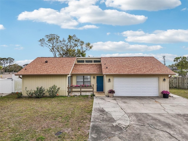 view of front facade with fence, roof with shingles, a front yard, a garage, and driveway