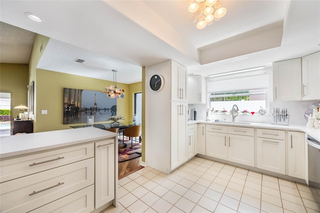 kitchen with a wealth of natural light, a notable chandelier, visible vents, and a sink