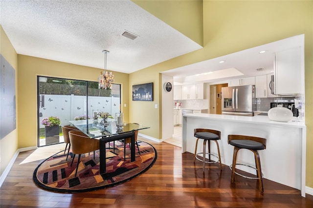 dining space with visible vents, baseboards, a chandelier, a textured ceiling, and wood-type flooring