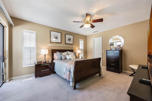 bedroom featuring visible vents, light carpet, a ceiling fan, a textured ceiling, and baseboards