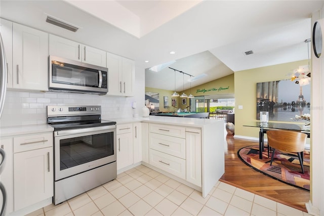 kitchen featuring visible vents, a peninsula, stainless steel appliances, and decorative backsplash