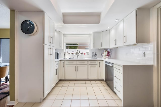 kitchen with tasteful backsplash, dishwasher, light countertops, light tile patterned floors, and a sink