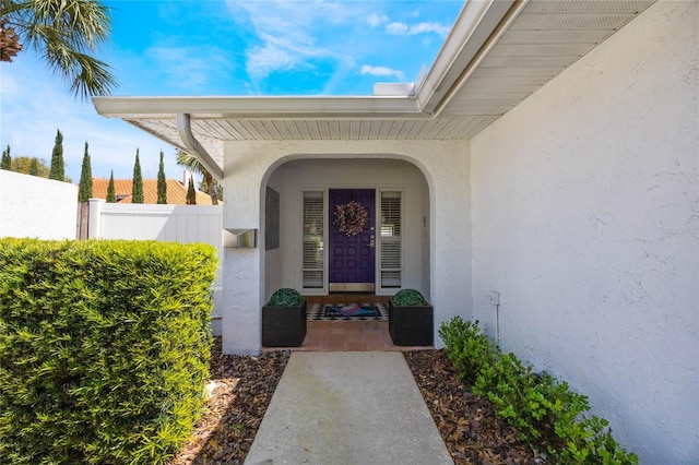 entrance to property with fence and stucco siding