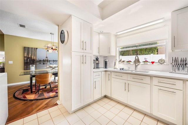 kitchen with a sink, visible vents, white cabinets, and light countertops