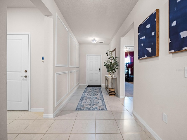 entryway featuring visible vents, baseboards, a textured ceiling, and light tile patterned flooring