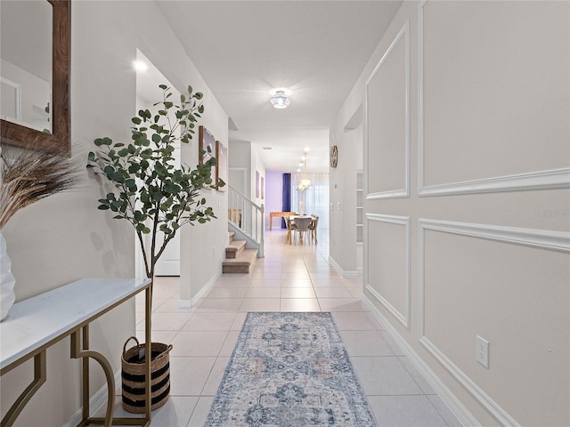 hall with light tile patterned floors, stairway, and baseboards