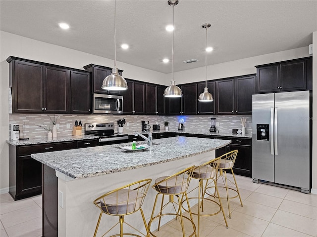 kitchen with light tile patterned floors, light stone countertops, visible vents, a sink, and appliances with stainless steel finishes