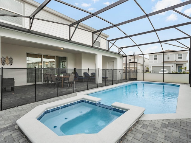 view of pool with a patio area, glass enclosure, and a pool with connected hot tub