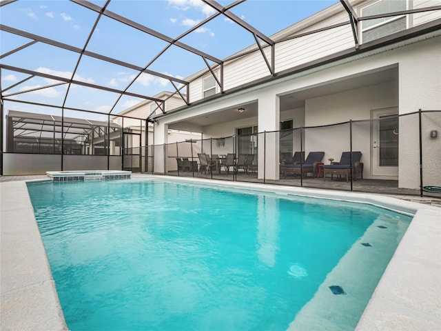 view of swimming pool featuring glass enclosure, a pool with connected hot tub, and a patio area