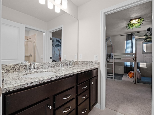 bathroom with a walk in closet, double vanity, a shower stall, and a sink