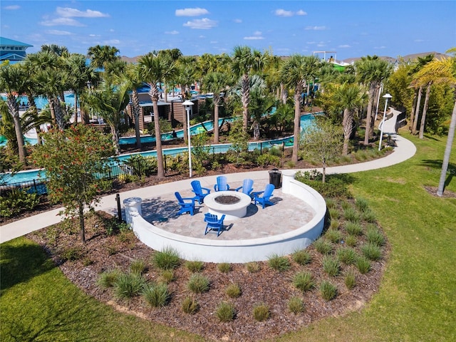 view of community with a patio, fence, a pool, a fire pit, and a lawn