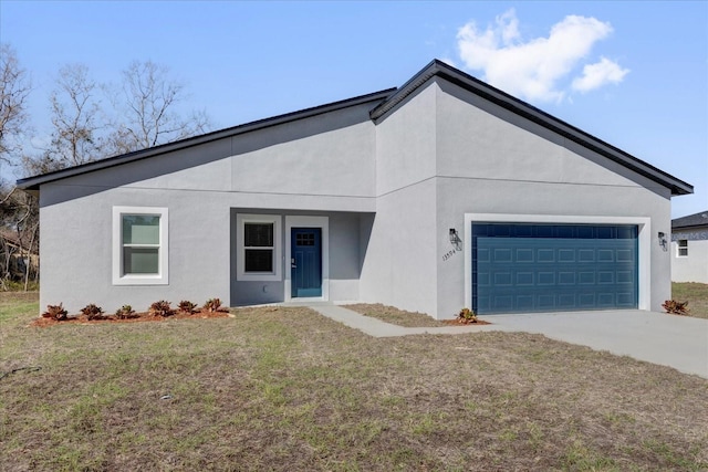 view of front of home featuring stucco siding, driveway, a front yard, and a garage