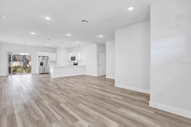 unfurnished living room featuring baseboards, visible vents, recessed lighting, a notable chandelier, and light wood-type flooring