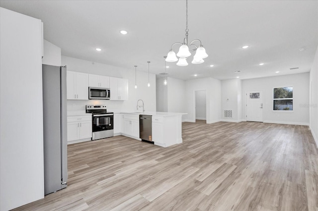 kitchen featuring visible vents, a peninsula, stainless steel appliances, open floor plan, and light wood-type flooring