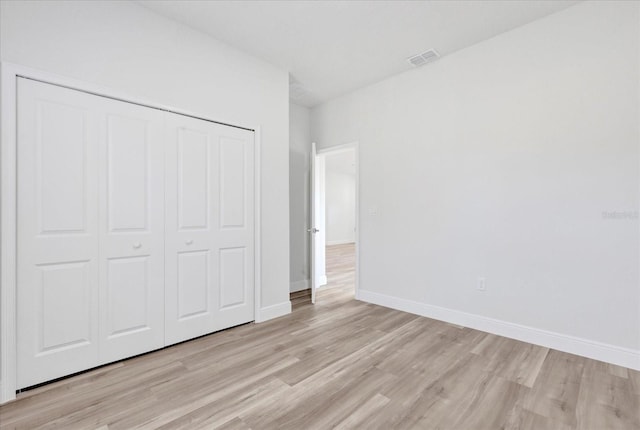 unfurnished bedroom with visible vents, baseboards, light wood-style floors, and a closet