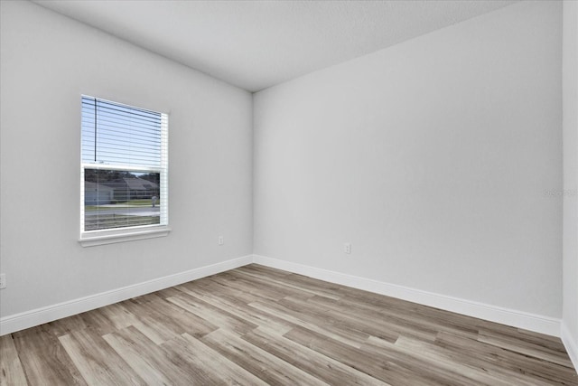 spare room with light wood-type flooring and baseboards