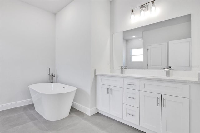 full bath featuring baseboards, double vanity, a freestanding tub, a sink, and tile patterned floors