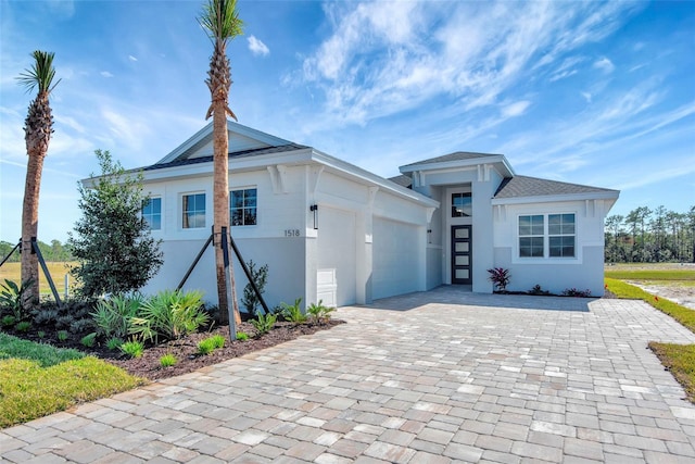 view of front of property featuring stucco siding, a shingled roof, decorative driveway, and a garage