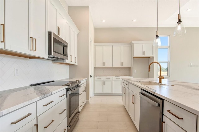 kitchen with white cabinetry, light stone counters, appliances with stainless steel finishes, and a sink