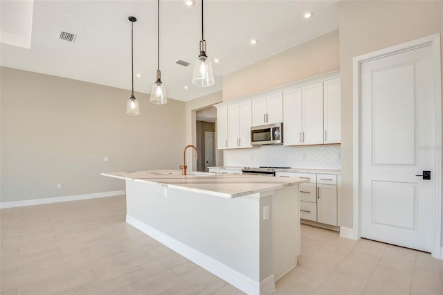 kitchen featuring visible vents, a kitchen island with sink, a sink, backsplash, and appliances with stainless steel finishes