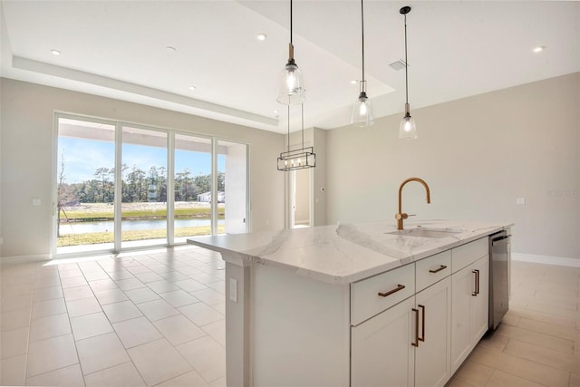 kitchen with light stone countertops, a tray ceiling, a sink, a water view, and stainless steel dishwasher